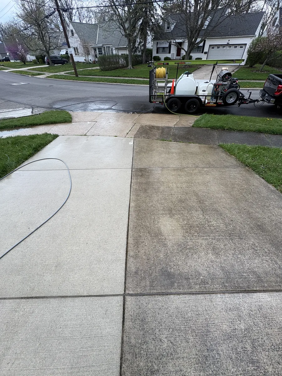 Concrete driveway being pressure washed with professional equipment